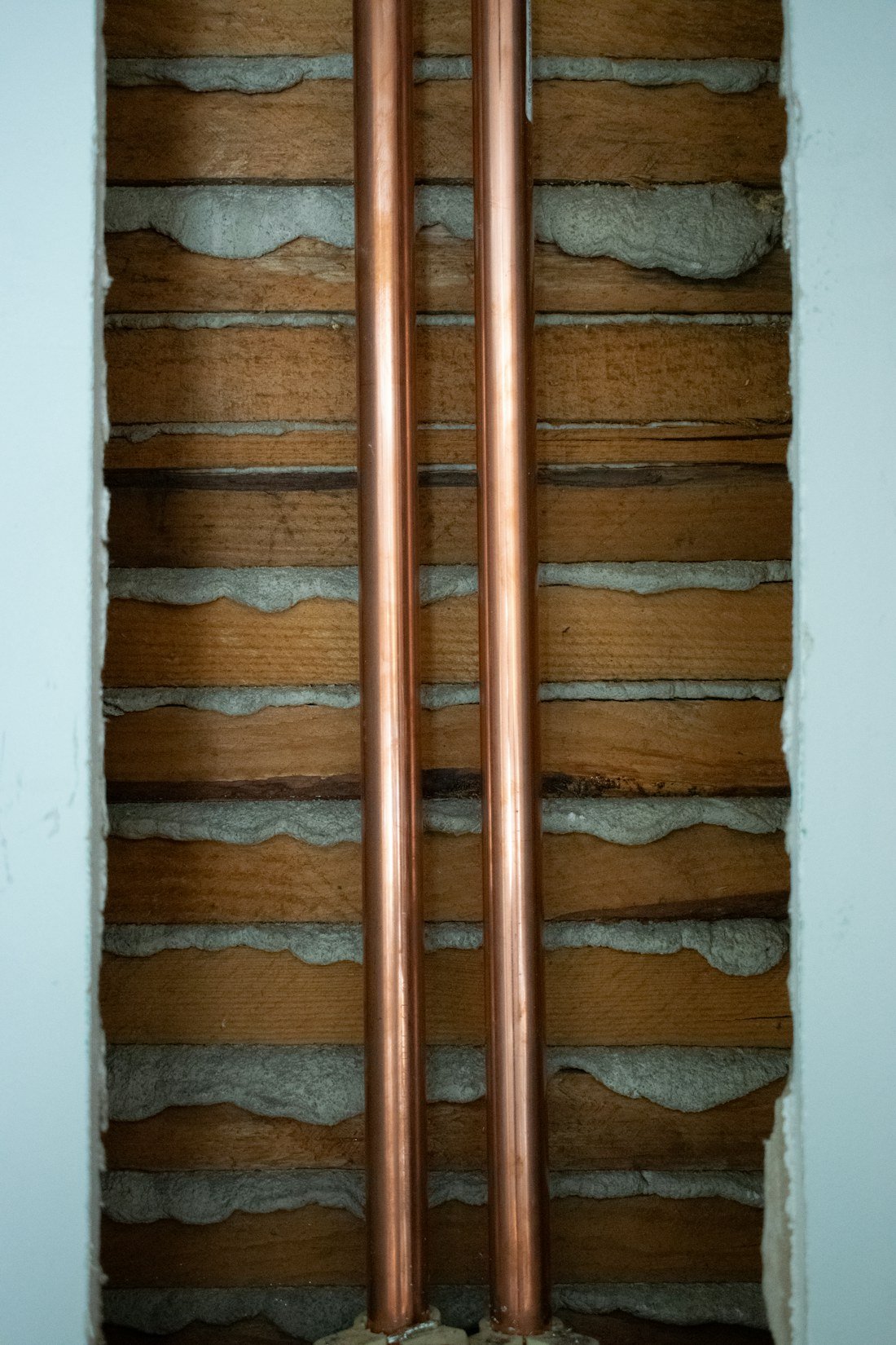 Exposed copper supply pipes running through a residential wall cavity