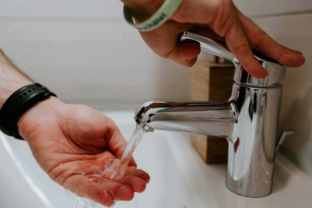 Hands testing a newly installed chrome faucet at a bathroom sink